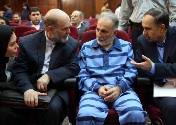 نجفي بالملابس المخططة يتحدث إلى محاميه